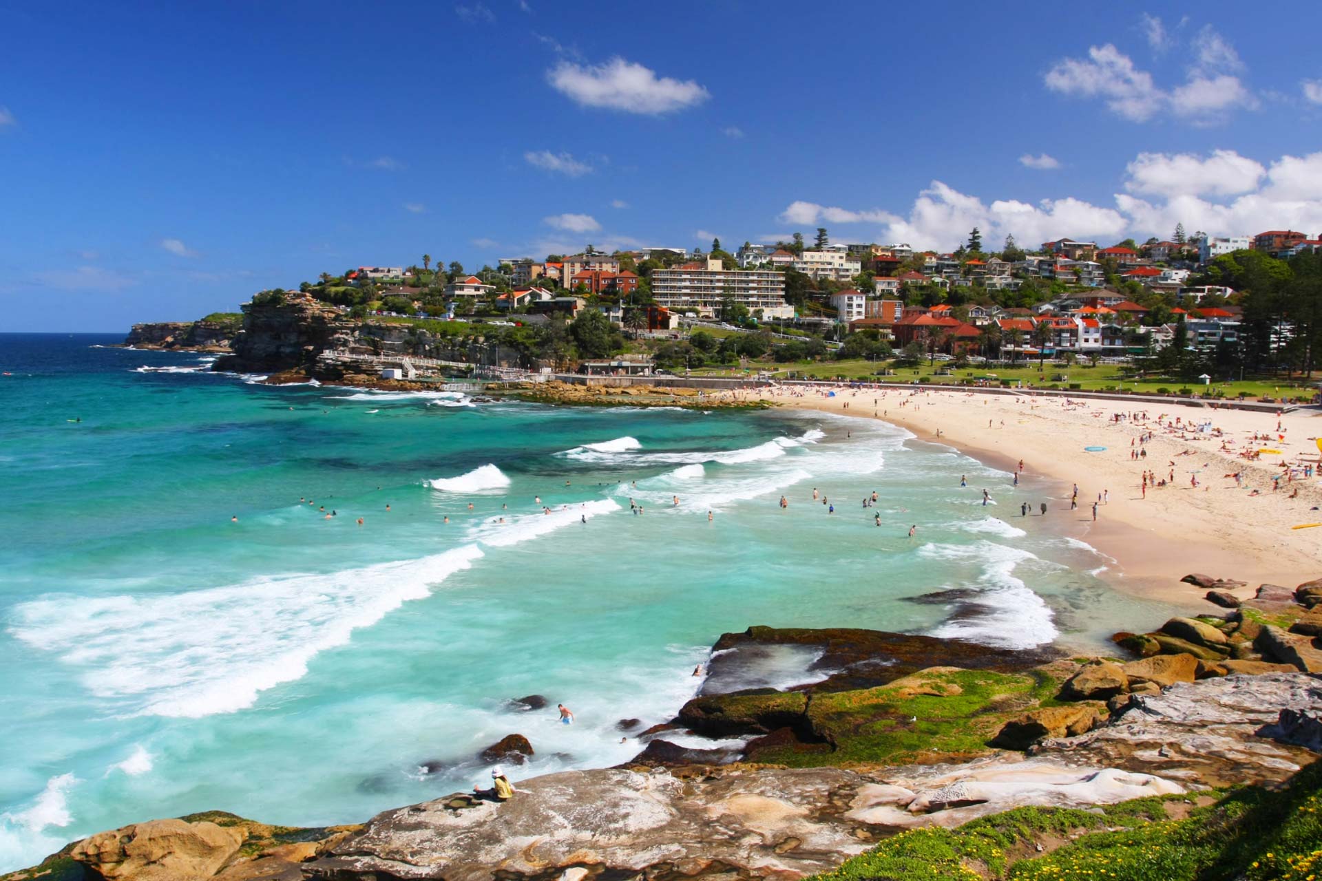 Town on hill rises behind beach in Australia.