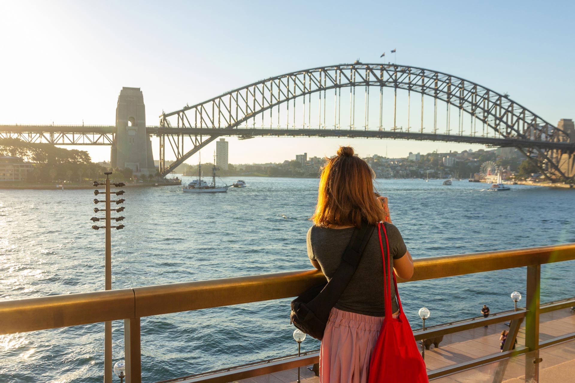 Woman looks across water toward bridge in Australia.
