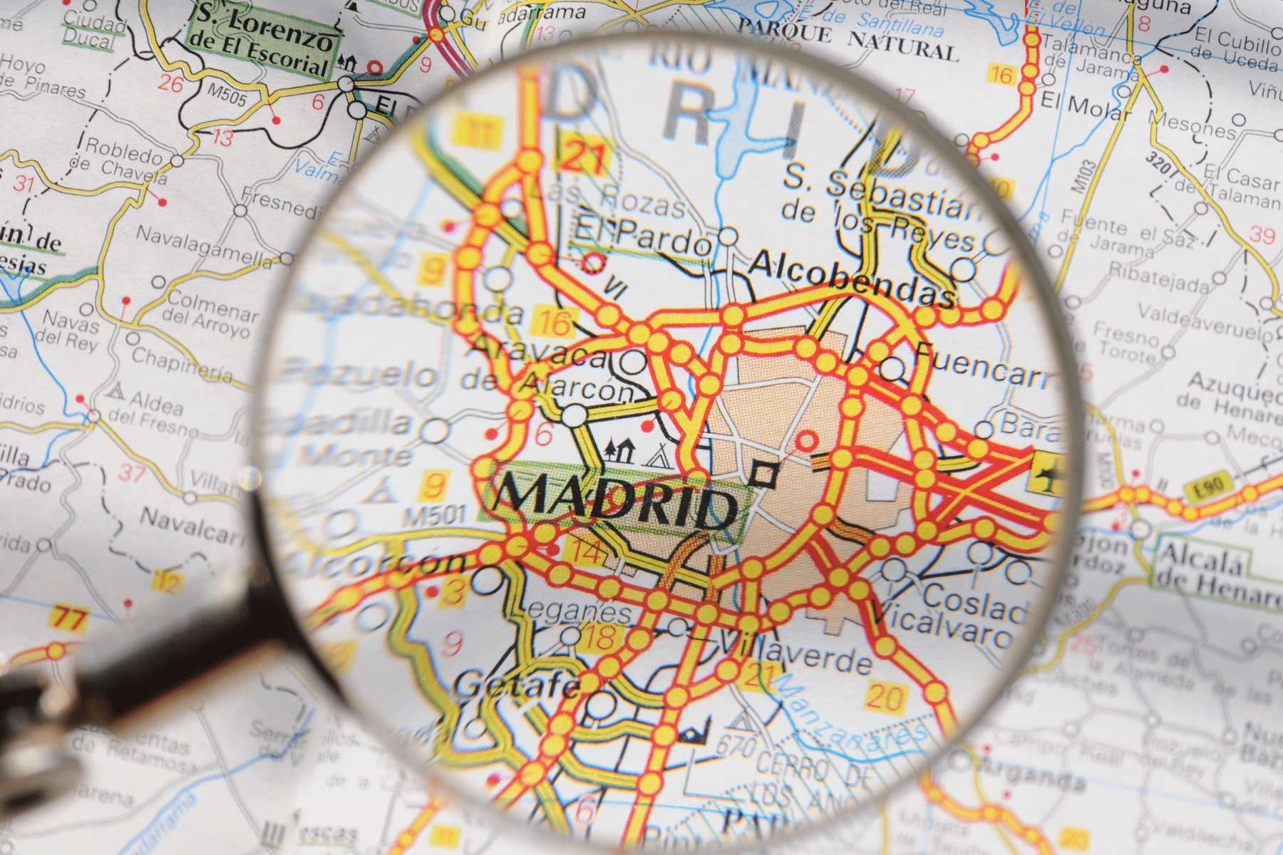 A magnifying glass is above Madrid on a map.
