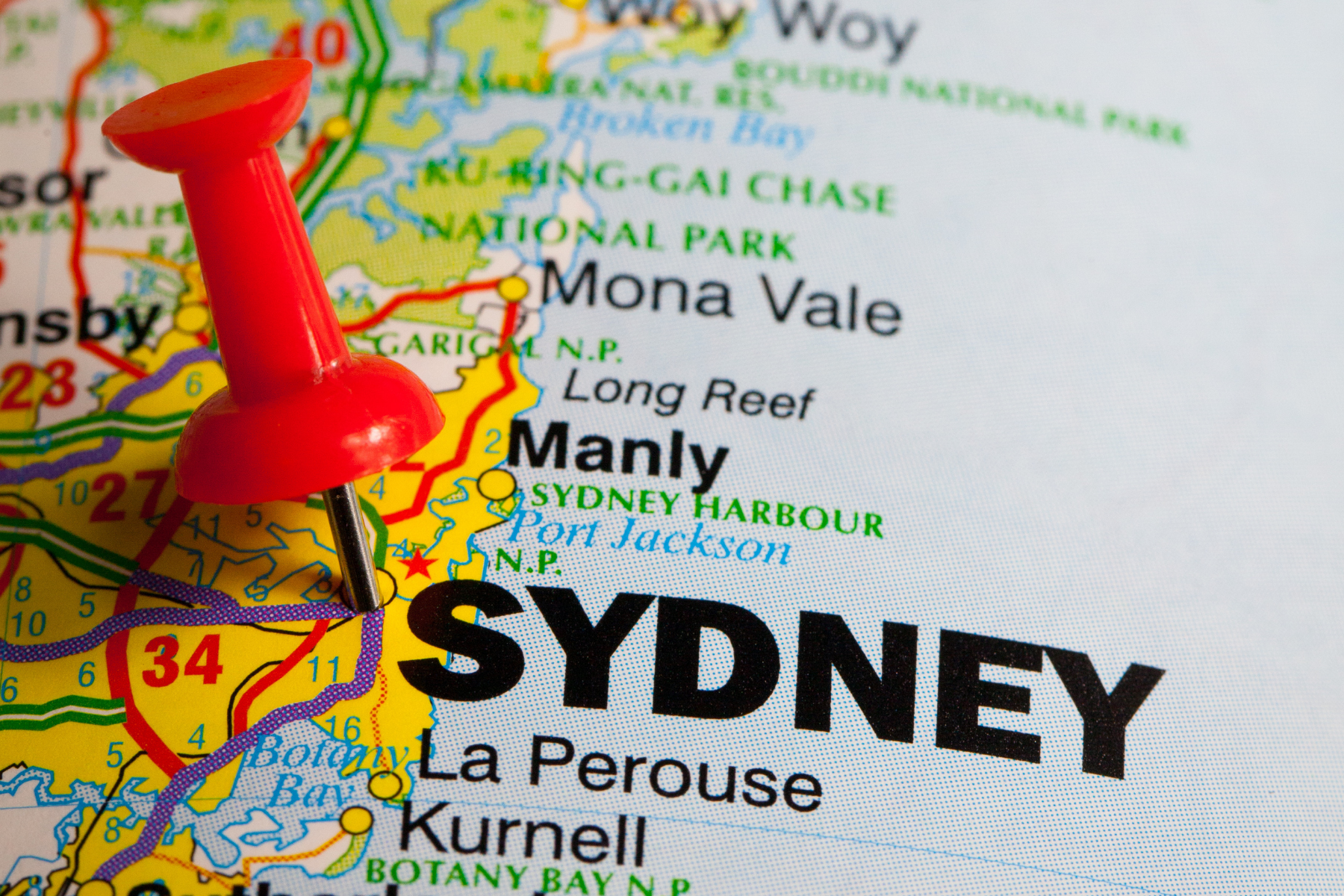 A close up shot of Sydney on a map with a red thumbtack stuck in it.