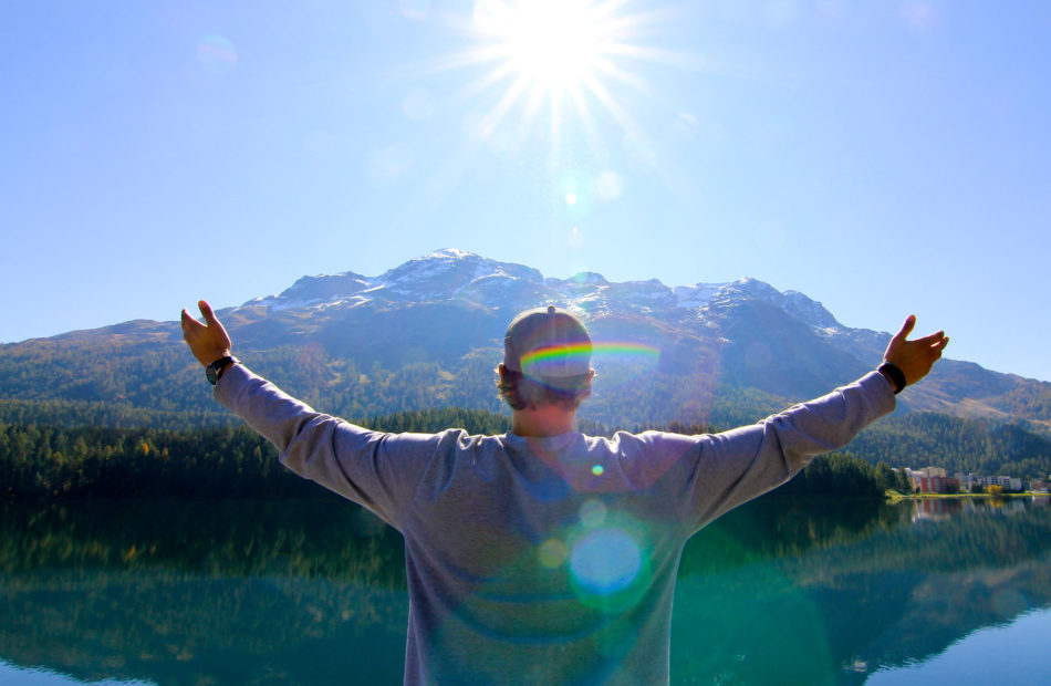 Man holds arms out in front of mountain.