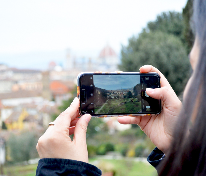 Woman takes photo of gardens on iPhone.