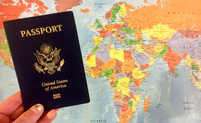 US passport held in front of world map.