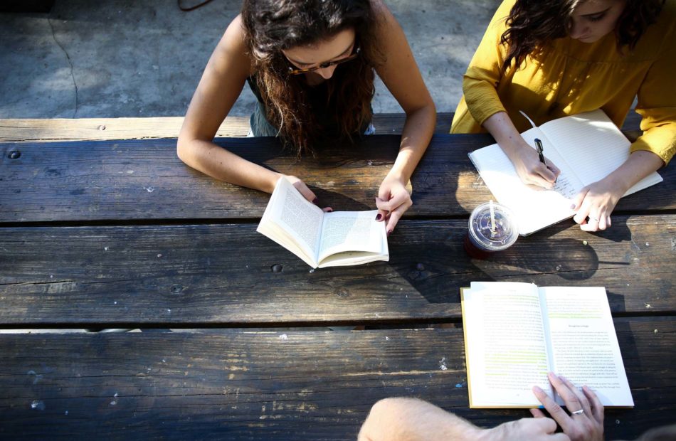 Students sit at picnic table to study.